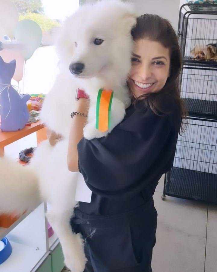 Dra. Sara Burrini segurando um filhote de spitz branco no colo