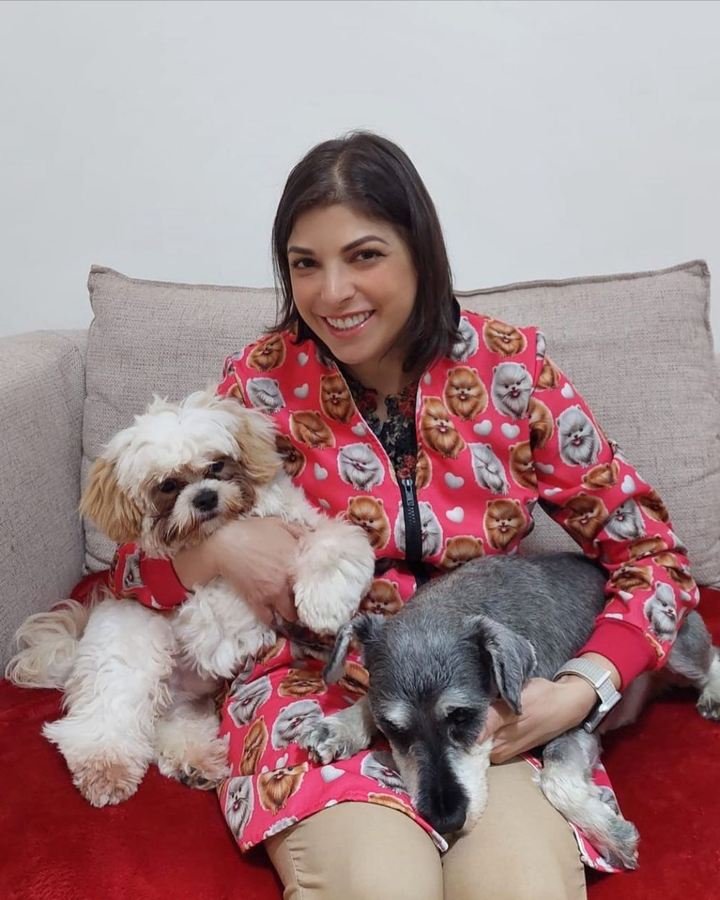Dra. Sara Burrini no sofá com dois cães no colo